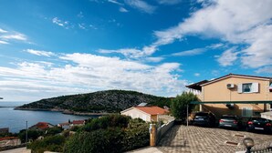 Et kystnært boligområde med huse, parkerede biler og frit kig til havet.
