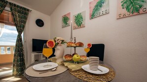 Et spisebord med tallerkener, bestik, en vase med blomster, en skål med frugt og et lys.