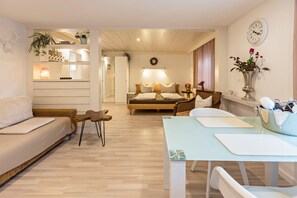 A modern living room with a sofa, a dining table, and a bed with a headboard.