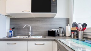 A modern kitchen with a stainless steel sink, a black microwave, and a coffee maker.