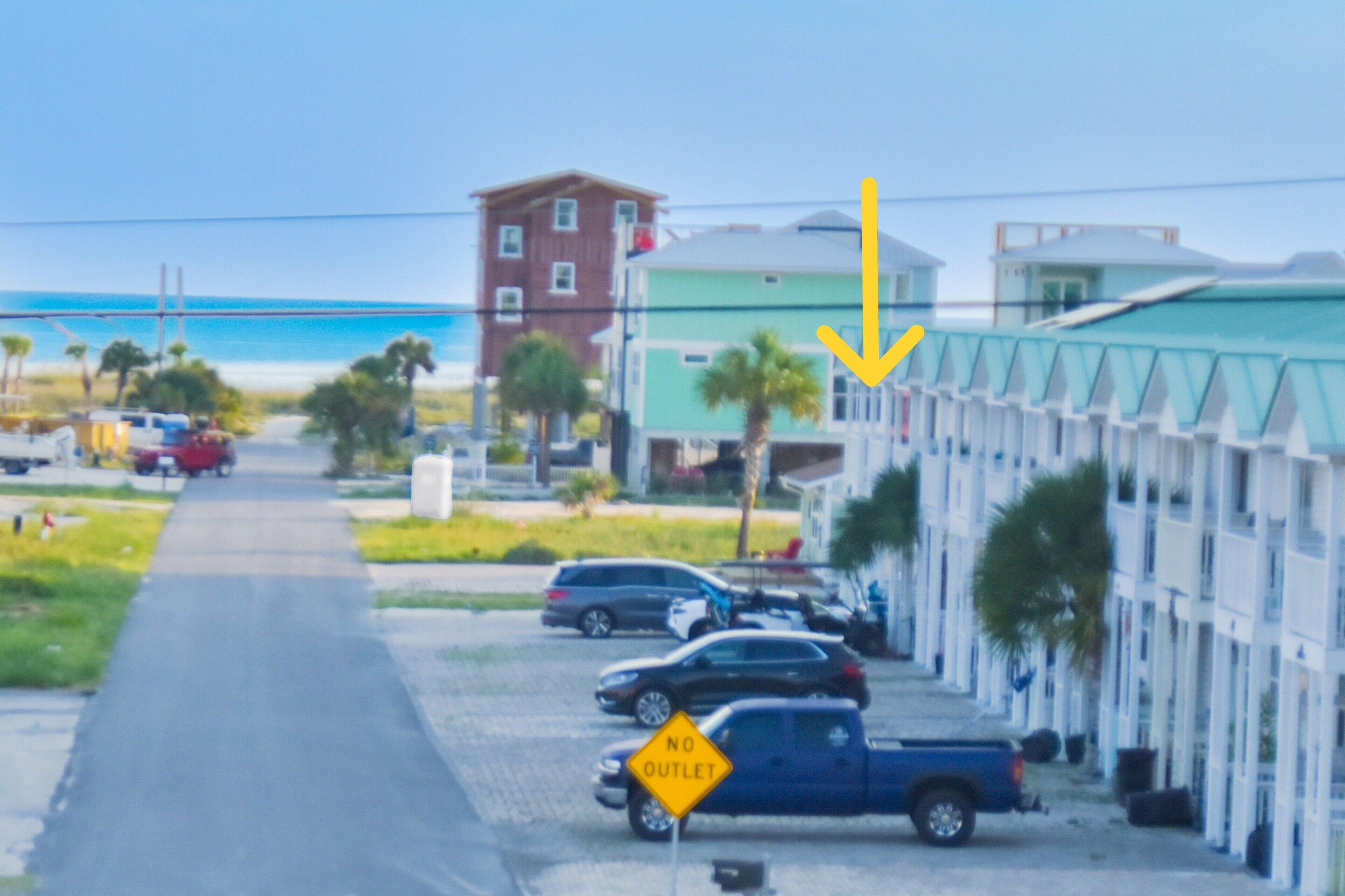 A street view with parked cars, a 'No Outlet' sign, and buildings along the road.