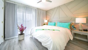 Une chambre d’hôtel moderne dotée d’un grand lit, d’un ventilateur de plafond, d’une table de chevet avec une lampe et d’une statuette d’oiseau décorative.