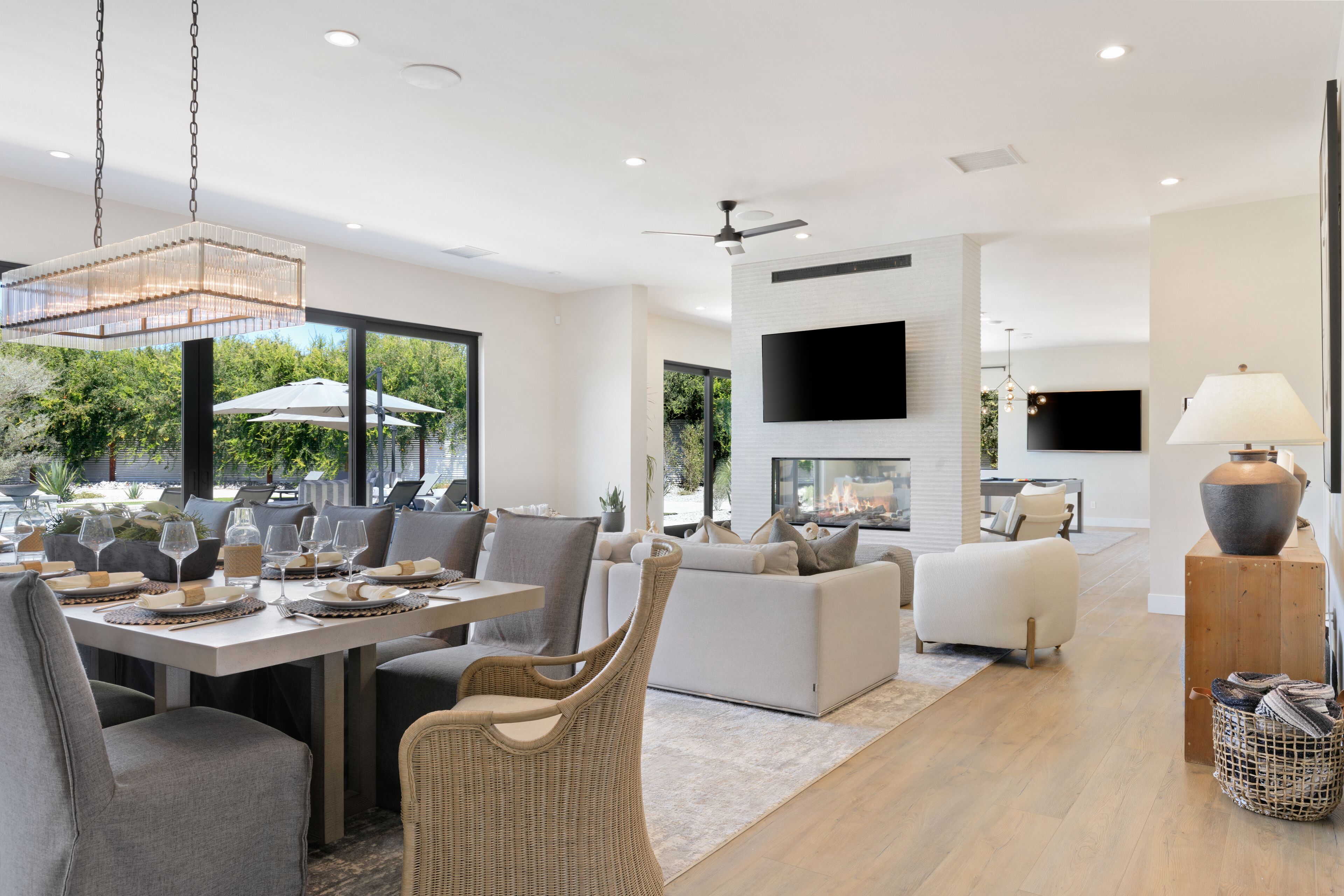 A modern living room with a dining area, a fireplace, and a flat-screen TV mounted on the wall.