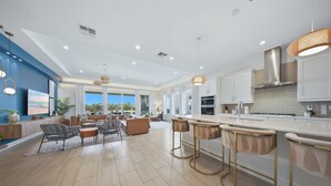 A spacious kitchen with modern appliances, a dining area with bar stools, and a living room with a large window. - 5BR Reunion Estate | Private Pool & Golf Views (Kissimmee)