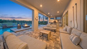 A spacious outdoor living area with a pool, seating, and a kitchen. - 5BR Reunion Estate | Private Pool & Golf Views (Kissimmee)