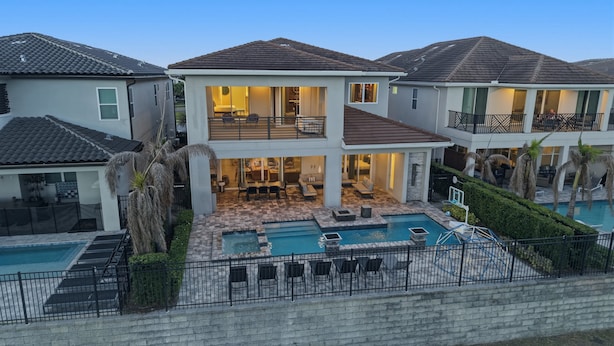 A multi-story residential building with a swimming pool, outdoor seating, and a balcony. - 5BR Reunion Estate | Private Pool & Golf Views (Kissimmee)