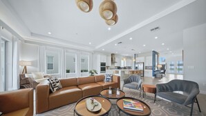 A spacious living area with a brown leather sofa, two round coffee tables, and a grey armchair. - 5BR Reunion Estate | Private Pool & Golf Views (Kissimmee)