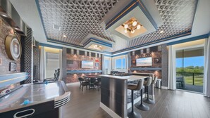 A modern kitchen with a bar area, a hot tub, and a dining space with a view. - 5BR Reunion Estate | Private Pool & Golf Views (Kissimmee)