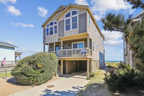 Een tweelaags pand aan het strand met een balkon, uitzicht op de oceaan en een bord met het nummer 136.