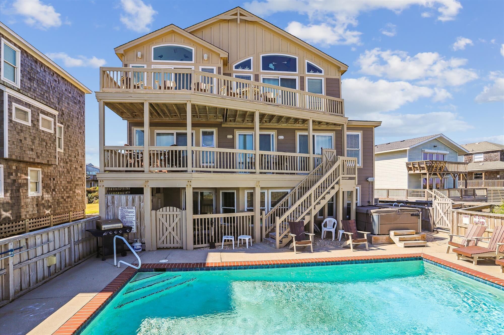 A multi-story building with a swimming pool, outdoor seating, and a covered deck area.