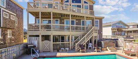 A multi-story building with a swimming pool, outdoor seating, and a covered deck area.