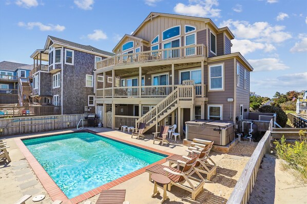 A multi-story building with a pool, outdoor seating, and a staircase leading to a balcony.