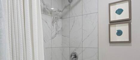 A bathroom with a bathtub, toilet, and two framed pictures on the wall.