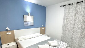 Ein Hotelzimmer mit Bett, Nachttisch, Wandleuchte, einem Gemälde und einer Duschvorhang.