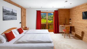 Una habitación con dos camas, un escritorio, una silla, un televisor y vistas a un paisaje verde.