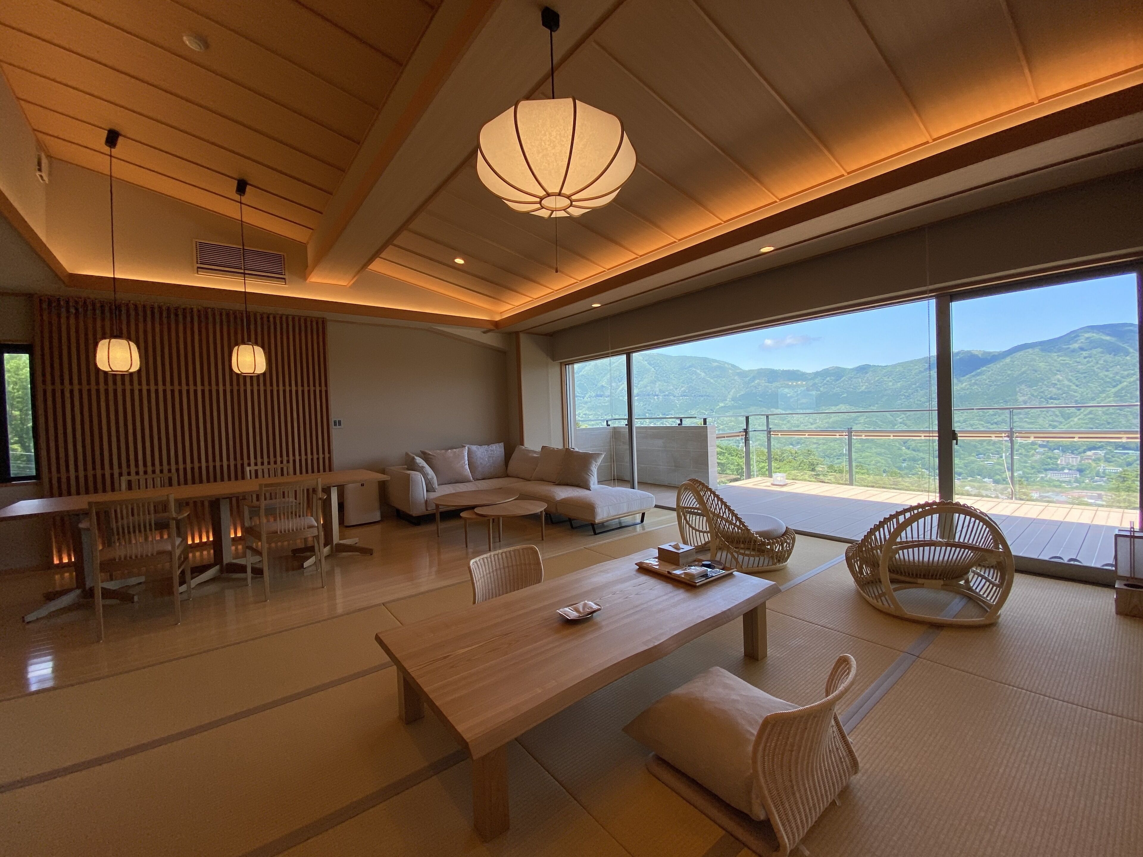 Una sala de estar moderna con un sofá, una mesa de madera y vistas a las montañas.