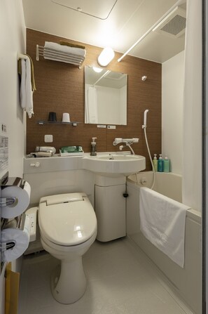 A compact bathroom with a toilet, sink, and shower.