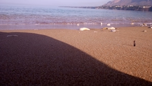 Ein Strand mit freiem Blick auf das Meer und entfernte Berge.