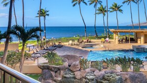 A resort pool area with palm trees, lounge chairs, and a view of the ocean. - Big Ocean View from your Sugar Beach Retreat -King Bed, Central AC, WiFi  #208 (Kihei)