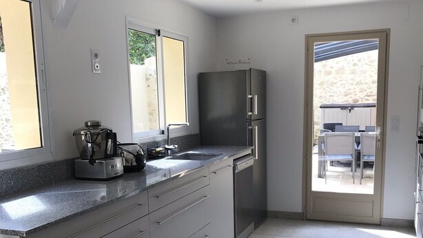 Una cocina moderna con una isla grande, electrodomésticos de acero inoxidable y vistas a un patio exterior.