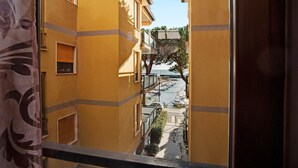 Una calle estrecha con edificios amarillos, un muelle para barcos y un árbol.