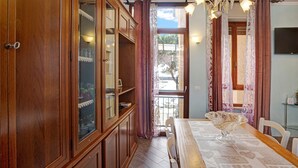 Comedor con una mesa de madera, sillas, una lámpara de araña y vistas a través de un ventanal.
