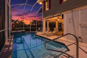 Piscina con vistas a la puesta de sol, mobiliario exterior y zona de terraza cubierta.