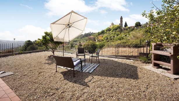 Eine Terrasse mit Tisch, Stühlen und Sonnenschirm.