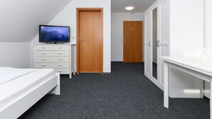 Een slaapkamer met een bed, een televisie op een dressoir, een kledingkast en een deur.