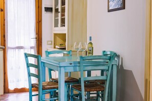 Une table à manger avec quatre chaises, une bouteille de vin et deux verres posés sur la table.