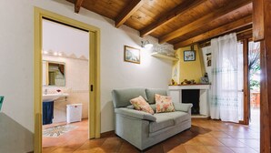 Een woonkamer met een bank, een open haard, een keukenhoek en een badkamer.