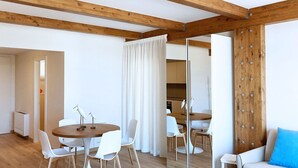 Une pièce moderne avec des poutres en bois, une table à manger avec des chaises, un canapé avec un coussin bleu et un grand miroir.