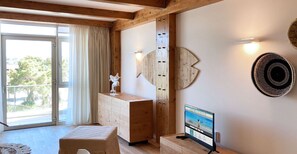 Une chambre moderne avec un plafond en bois, une grande fenêtre avec des rideaux, un meuble en bois, une petite table avec un téléviseur et un élément décoratif mural.