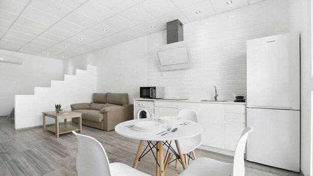 A modern kitchen with white cabinetry, a built-in microwave, and a refrigerator.