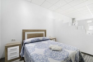 Une chambre à coucher avec un lit, des tables de chevet, une tête de lit en bois et une fenêtre.