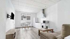 Ein moderner, minimalistischer Wohnraum mit Küche, Essbereich und Sitzgelegenheit.