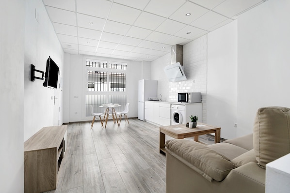 Un espace de vie moderne et minimaliste comprenant une cuisine, un coin repas et un espace détente.