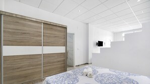 Ein modernes Schlafzimmer mit einem großen Bett, einem Holzschrank und einem an der Wand befestigten Fernseher.