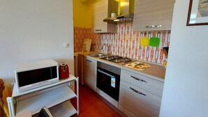 A compact kitchen with a gas stove, oven, and a small countertop. - Luisa 5B - Cozy three rooms apartment (Lido di Pomposa)