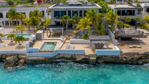 Un resort costero con piscina, áreas de descanso y vista al océano.
