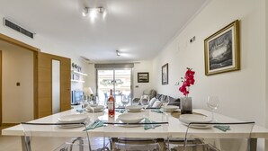 A dining area with a long table set for six, clear chairs, and a bottle of wine. - MARJALETA, Beautiful apartment in the centre of Moraira for 4 pax free wifi. (Moraira)