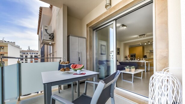 A balcony with a dining table, chairs, a small refrigerator, and a glass door leading to an interior space with a sofa and a kitchen area. - MARJALETA, Beautiful apartment in the centre of Moraira for 4 pax free wifi. (Moraira)