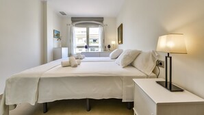 A hotel room with a large bed, bedside tables, a lamp, and a window with curtains. - MARJALETA, Beautiful apartment in the centre of Moraira for 4 pax free wifi. (Moraira)