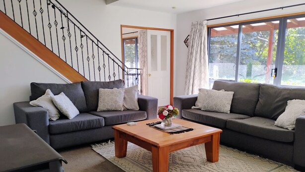 A living room with two grey sofas, a wooden coffee table, and a staircase.