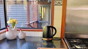 A kitchen with a stainless steel stove, a sink, and a window with a view of a brick building and a wooden deck.