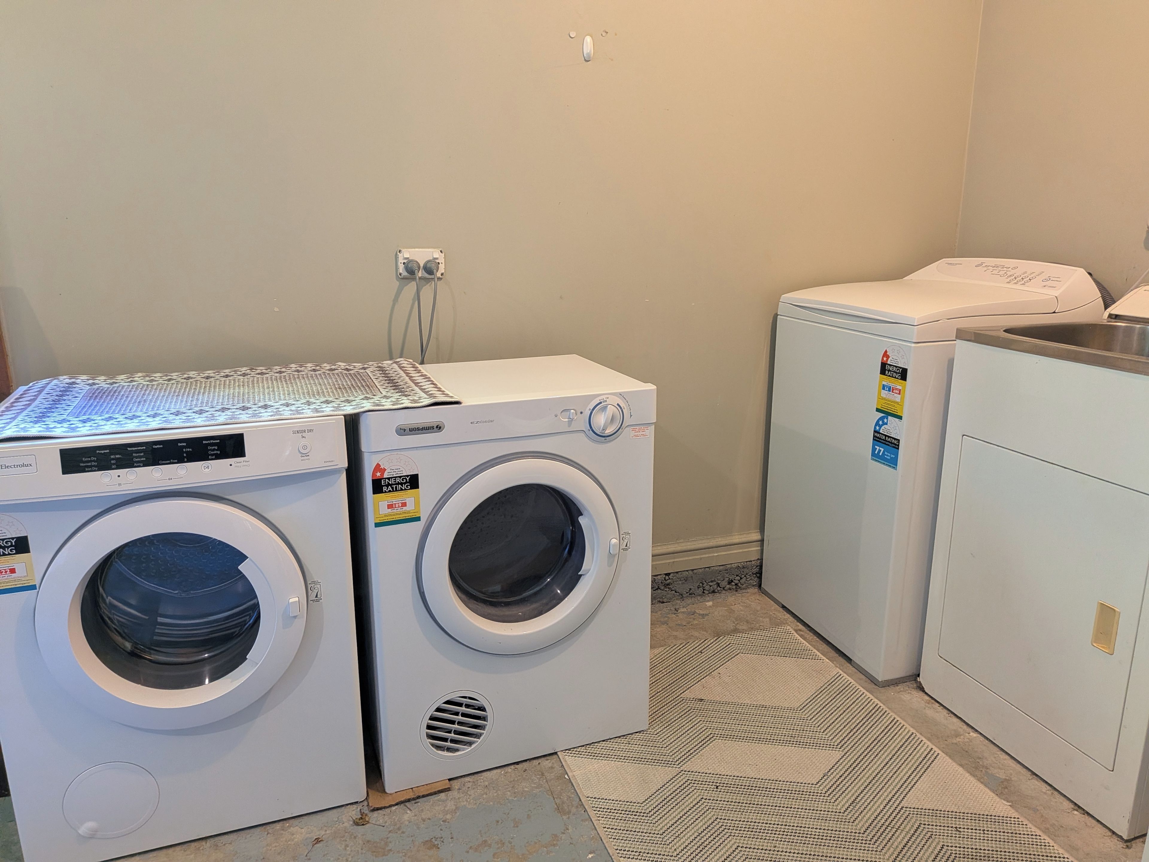 A laundry room with two front-loading washing machines and a dryer.
