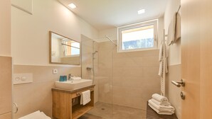 A modern bathroom with a glass-enclosed shower, a sink with a wooden vanity, and a window providing natural light. - Studio in der Alpine Lodge Arlberg (Klösterle am Arlberg)