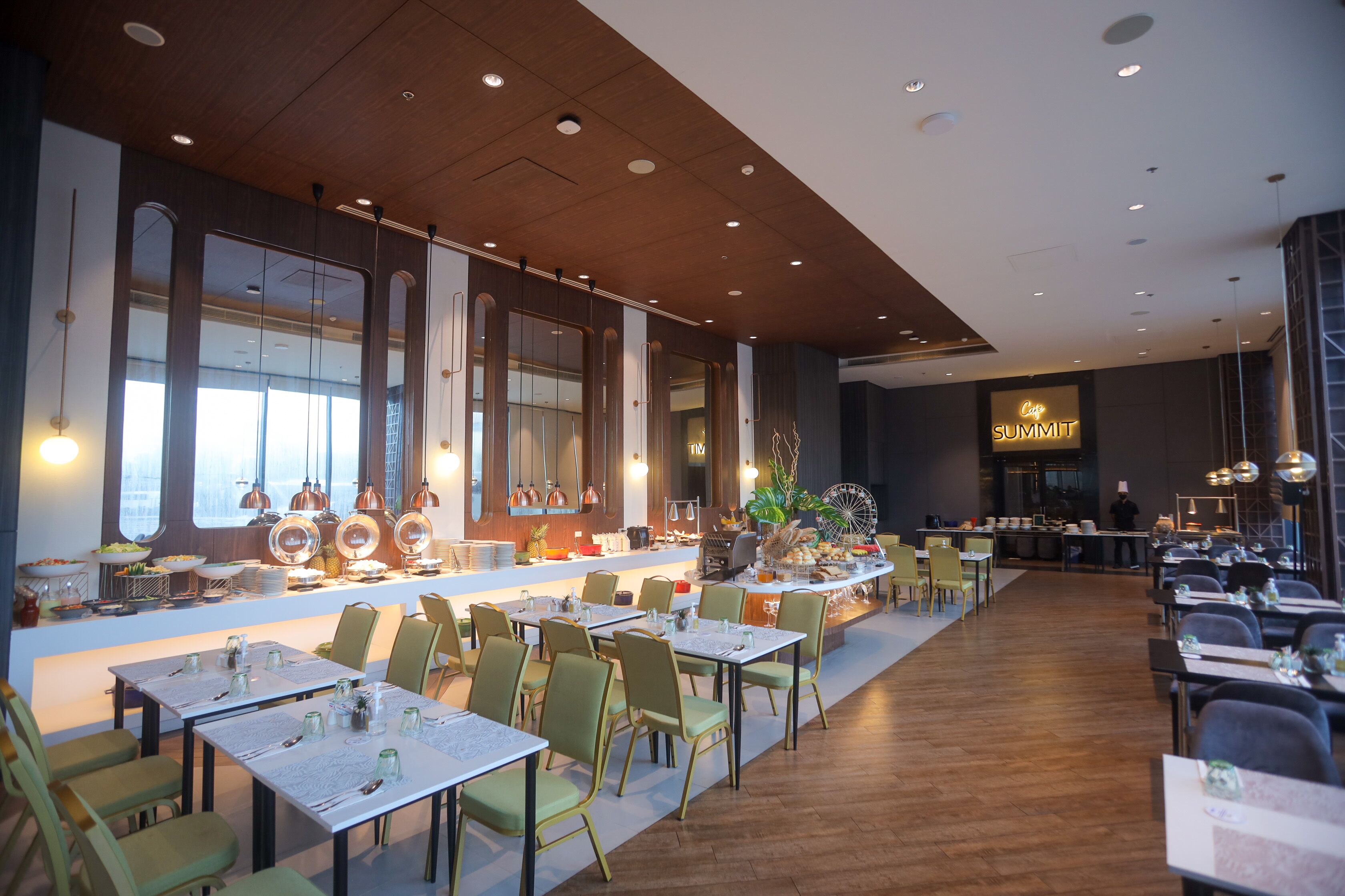 A modern restaurant with a long counter, multiple tables, and chairs.