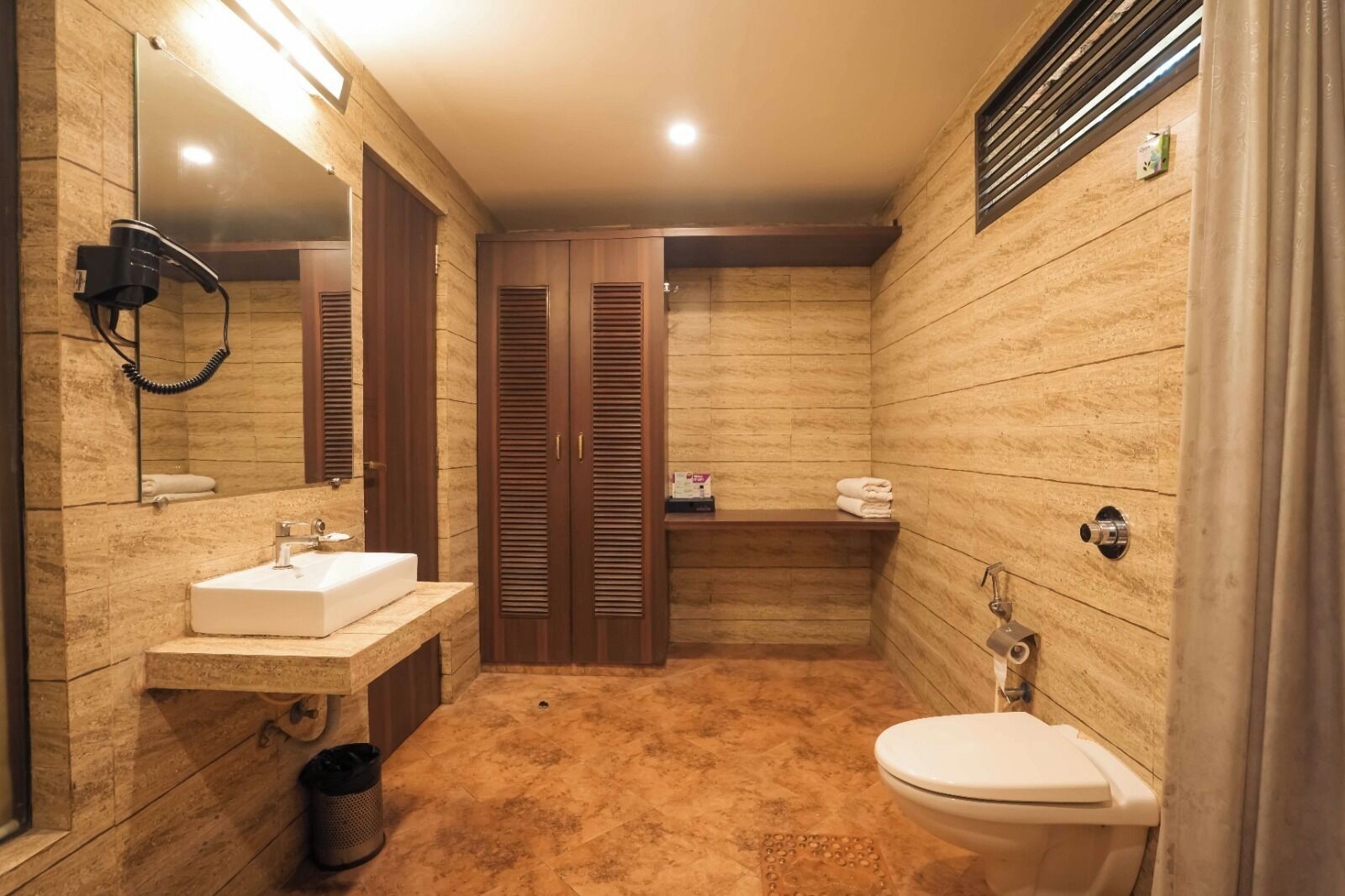 A bathroom with a sink, mirror, toilet, and wooden cabinets.