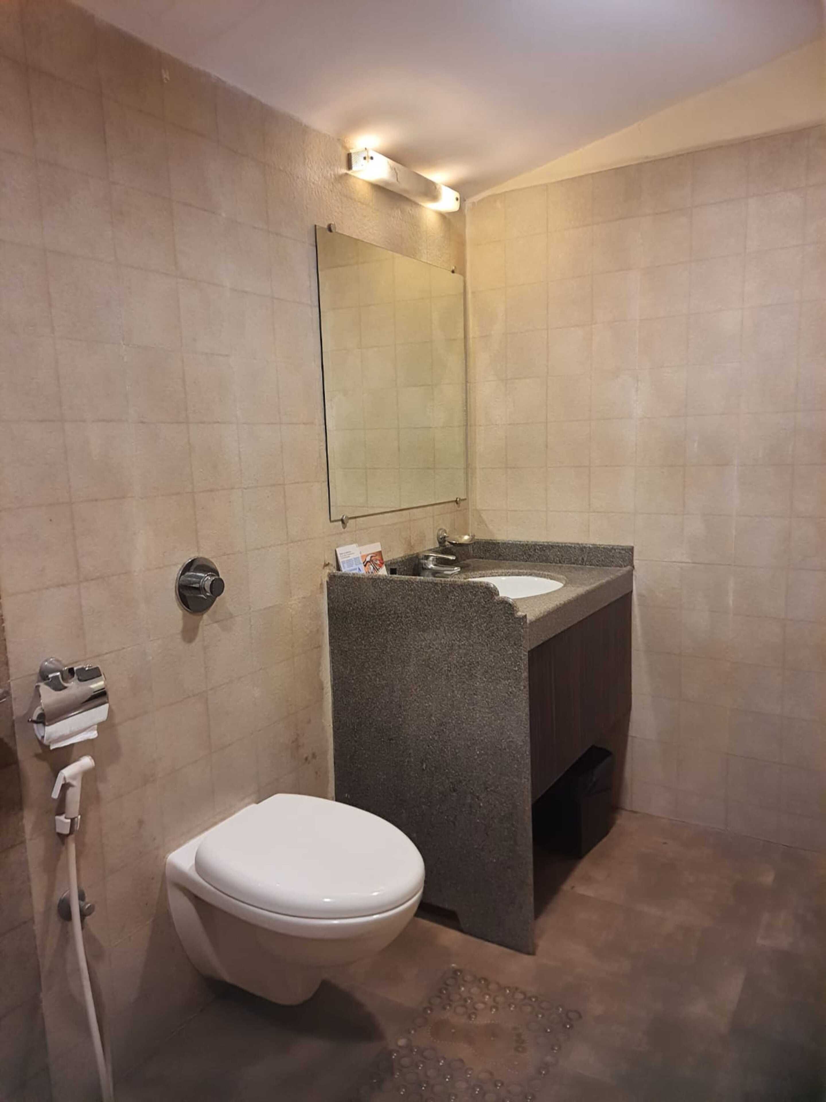 A bathroom with a toilet, sink, and mirror.